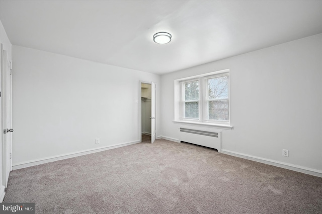 unfurnished bedroom with carpet floors, radiator heating unit, and a closet