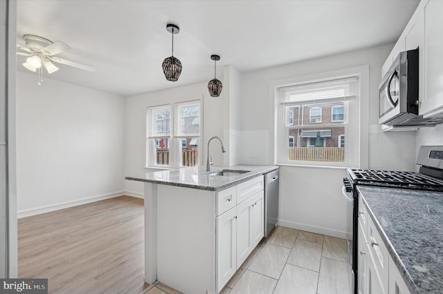 kitchen with sink, white cabinetry, hanging light fixtures, appliances with stainless steel finishes, and stone counters