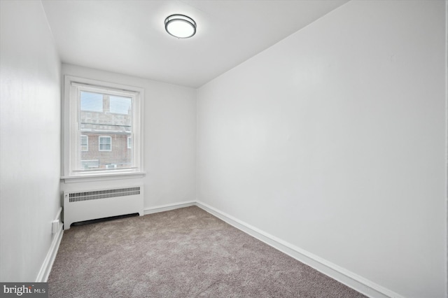 carpeted empty room featuring radiator heating unit