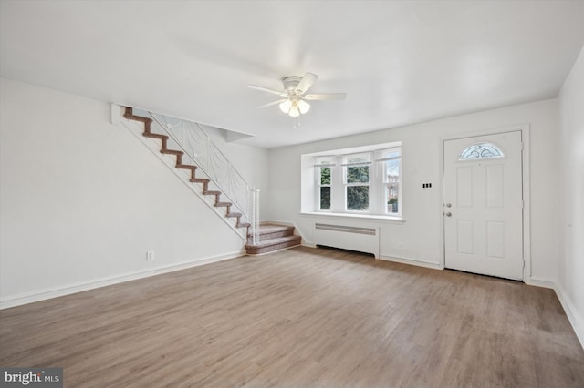 foyer entrance featuring radiator heating unit, ceiling fan, and light hardwood / wood-style flooring