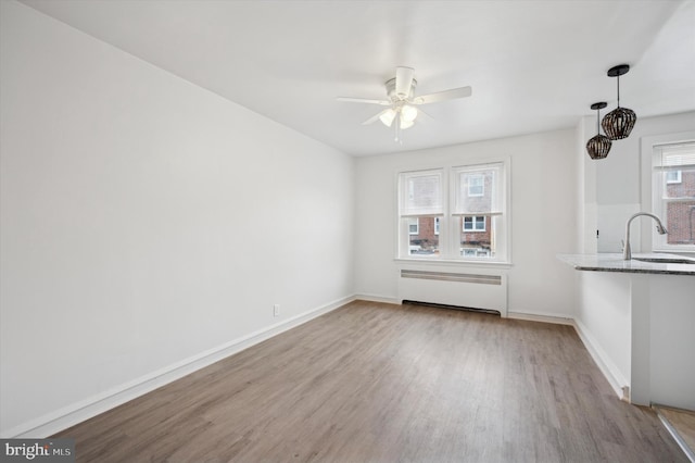 interior space with ceiling fan, radiator, sink, and light wood-type flooring