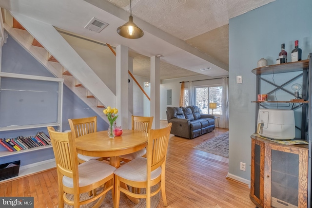 dining space featuring light hardwood / wood-style flooring and a textured ceiling