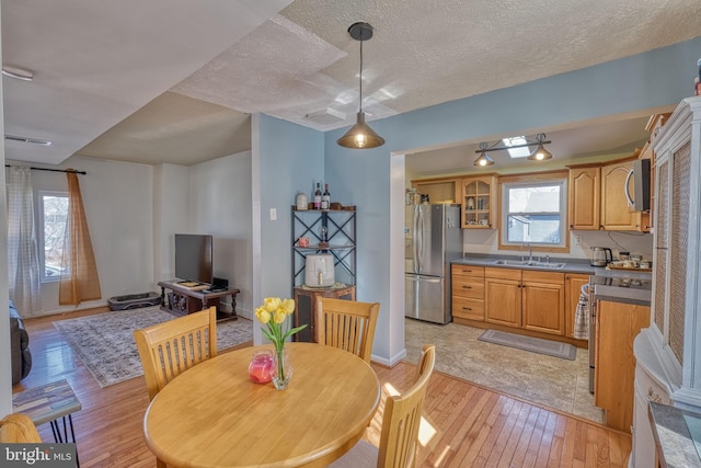 dining area featuring sink, light hardwood / wood-style flooring, and a textured ceiling