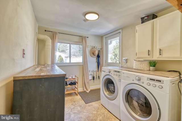 laundry area featuring washing machine and dryer, cabinets, and light tile patterned flooring