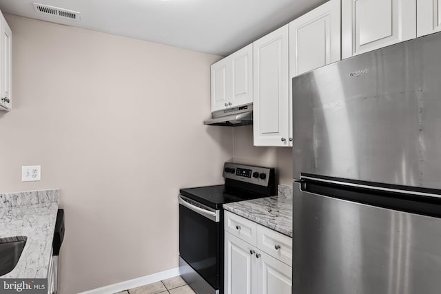 kitchen with light stone counters, light tile patterned flooring, white cabinets, and appliances with stainless steel finishes