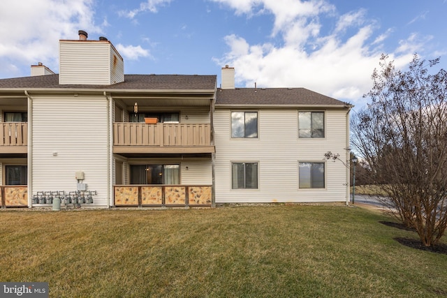 back of property featuring a balcony and a yard