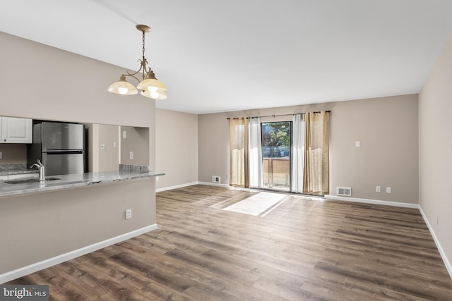 unfurnished living room featuring sink, a chandelier, and dark hardwood / wood-style floors