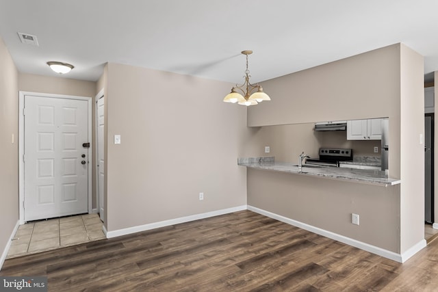 kitchen featuring an inviting chandelier, wood-type flooring, appliances with stainless steel finishes, pendant lighting, and white cabinets