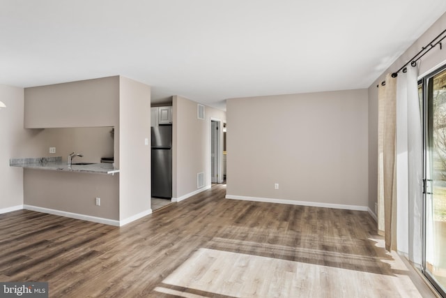 unfurnished living room with sink and wood-type flooring