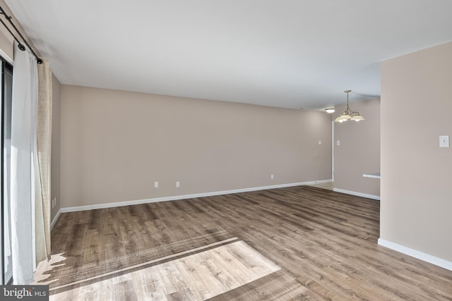 spare room with hardwood / wood-style flooring and a notable chandelier