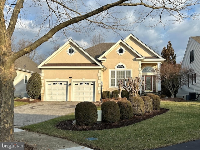 view of front of home featuring a garage, central AC, and a front lawn