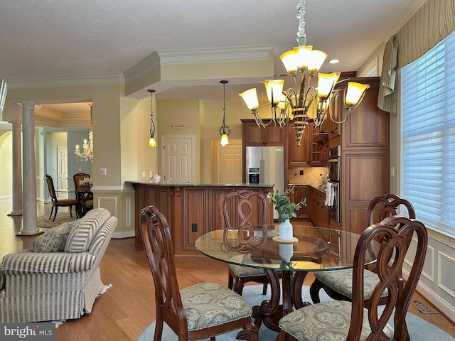 dining space featuring an inviting chandelier, crown molding, light wood-type flooring, a wealth of natural light, and decorative columns