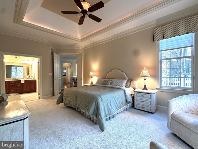 bedroom with light colored carpet, ornamental molding, a raised ceiling, and ensuite bathroom