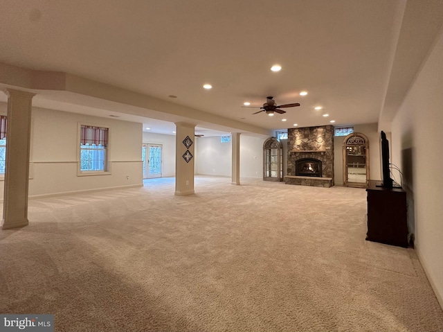 unfurnished living room featuring ornate columns, ceiling fan, light carpet, and a fireplace