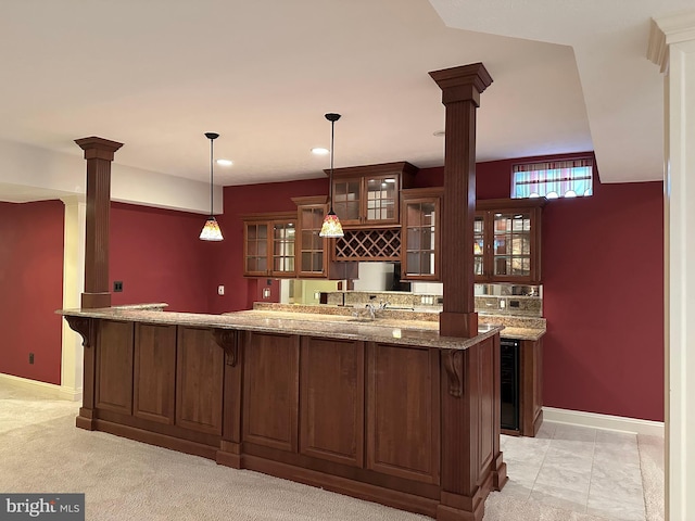 bar with decorative columns, light stone countertops, light carpet, and decorative light fixtures