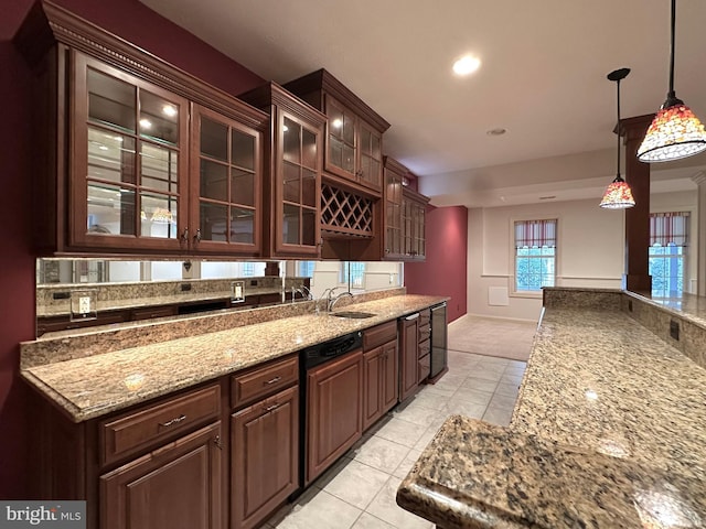 kitchen featuring pendant lighting, dark brown cabinetry, sink, and light stone counters