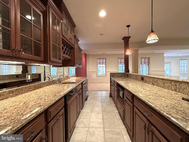 kitchen with built in microwave, sink, pendant lighting, and light stone counters