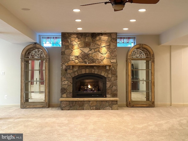 interior space with ceiling fan, plenty of natural light, a stone fireplace, and carpet