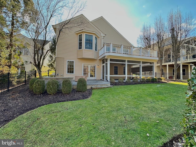 rear view of property with a balcony, a yard, a sunroom, a patio area, and french doors