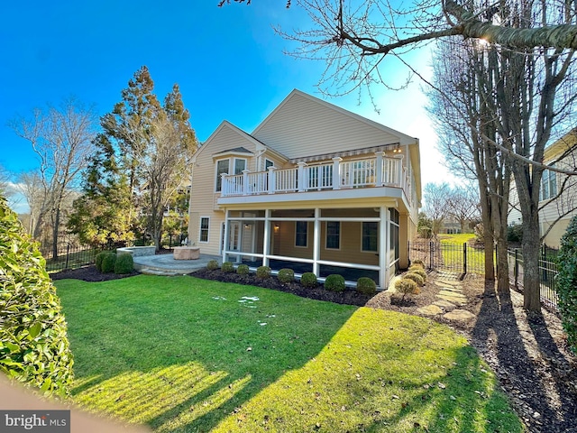 rear view of house with a balcony, a yard, a patio, and a sunroom