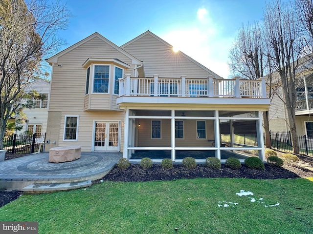 rear view of property with a hot tub, a balcony, a sunroom, and a lawn