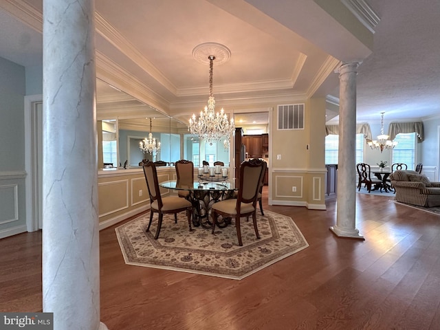 dining room featuring ornamental molding, a chandelier, decorative columns, and wood-type flooring