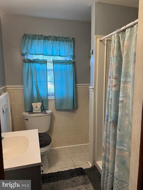 bathroom with tile patterned flooring, tile walls, curtained shower, and vanity