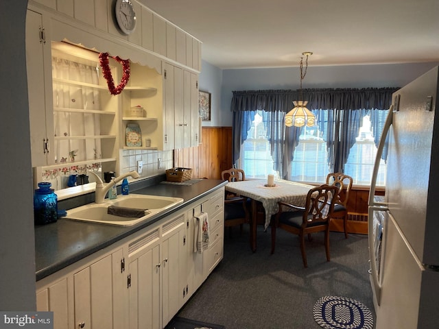 kitchen featuring open shelves, dark colored carpet, dark countertops, white cabinets, and a sink