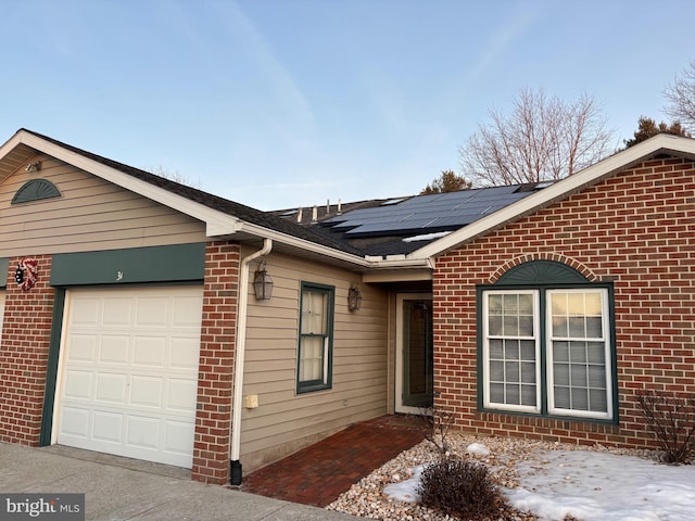 ranch-style home with a garage and solar panels