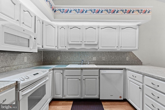 kitchen with wood-type flooring, sink, white cabinets, and white appliances