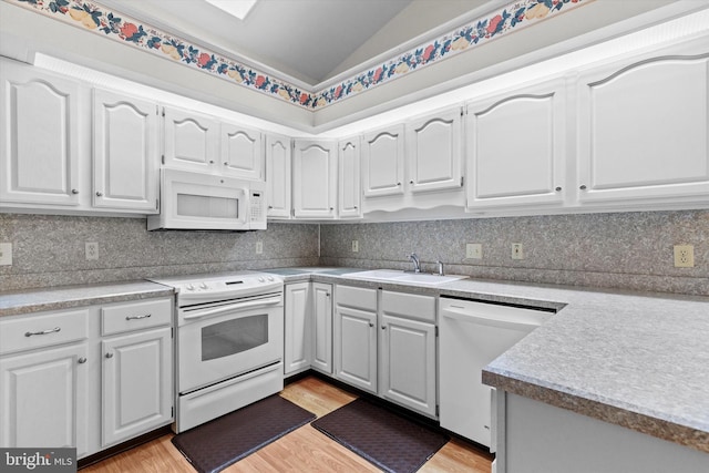 kitchen featuring vaulted ceiling, white cabinetry, sink, decorative backsplash, and white appliances