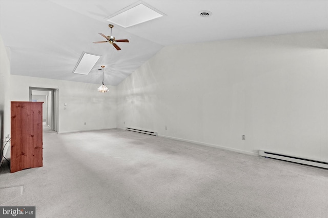 spare room featuring light carpet, ceiling fan with notable chandelier, a baseboard radiator, and vaulted ceiling with skylight