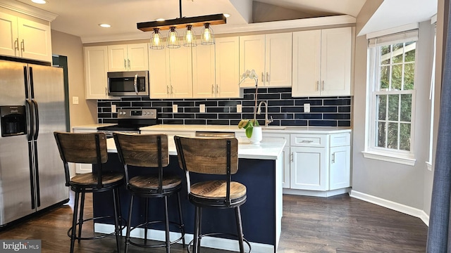 kitchen with decorative light fixtures, white cabinetry, sink, a center island, and stainless steel appliances