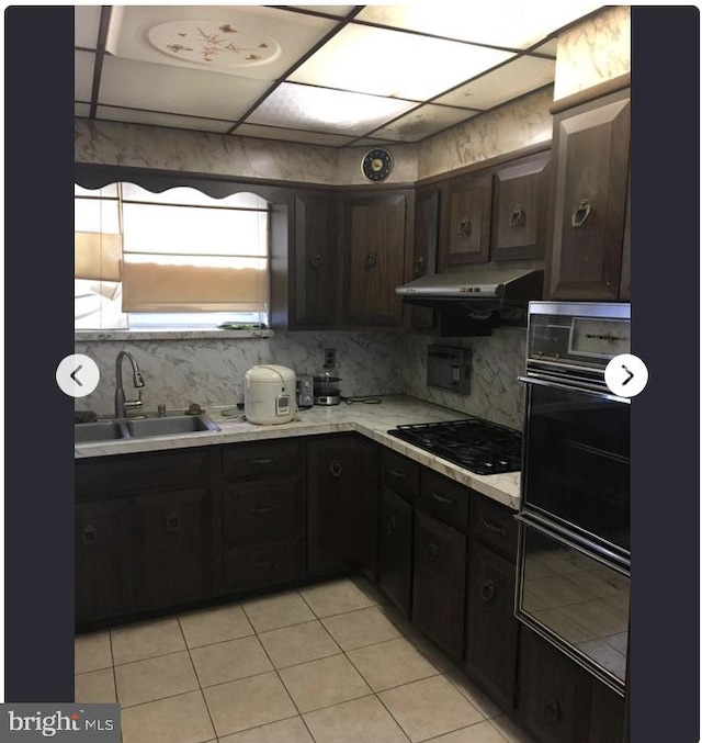 kitchen with dark brown cabinetry, sink, decorative backsplash, and black appliances