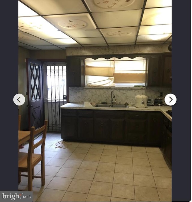 kitchen with sink, light tile patterned floors, and dark brown cabinets