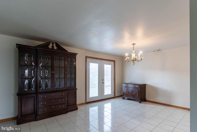 tiled empty room with french doors and a chandelier