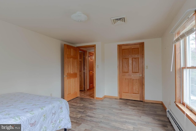 bedroom with light hardwood / wood-style flooring and a baseboard radiator