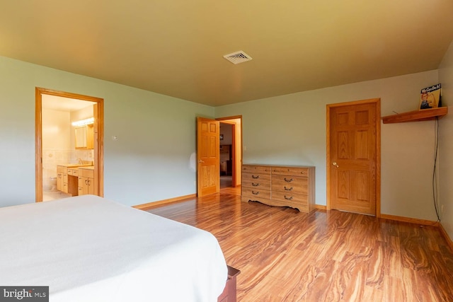 bedroom featuring connected bathroom and hardwood / wood-style flooring