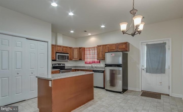 kitchen featuring appliances with stainless steel finishes, hanging light fixtures, a center island, light stone counters, and a notable chandelier