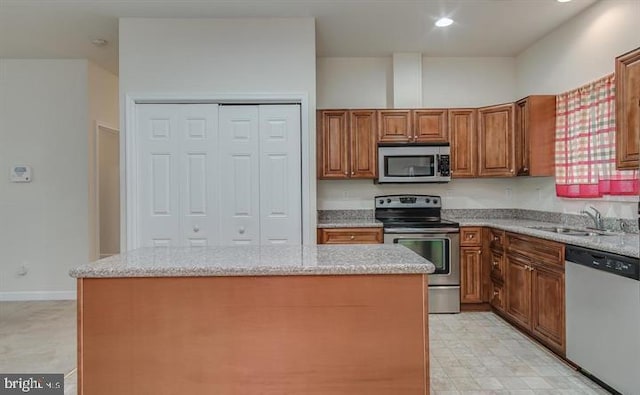 kitchen with stainless steel appliances, a kitchen island, and light stone counters