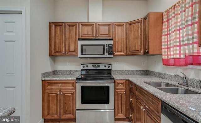 kitchen with light stone counters, stainless steel appliances, and sink