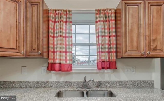 kitchen featuring light stone counters and sink