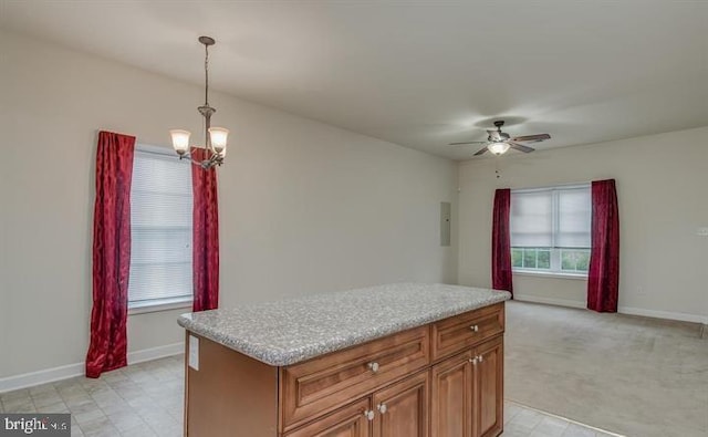 kitchen featuring ceiling fan with notable chandelier, light colored carpet, hanging light fixtures, and a kitchen island