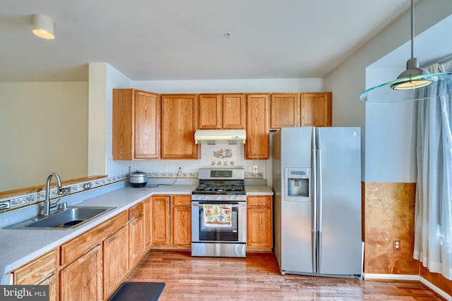 kitchen with sink, backsplash, hanging light fixtures, light hardwood / wood-style floors, and stainless steel appliances