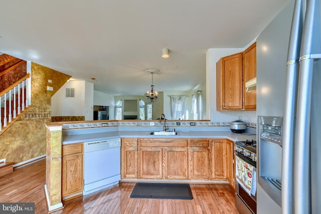 kitchen featuring sink, stainless steel appliances, light hardwood / wood-style floors, decorative light fixtures, and kitchen peninsula