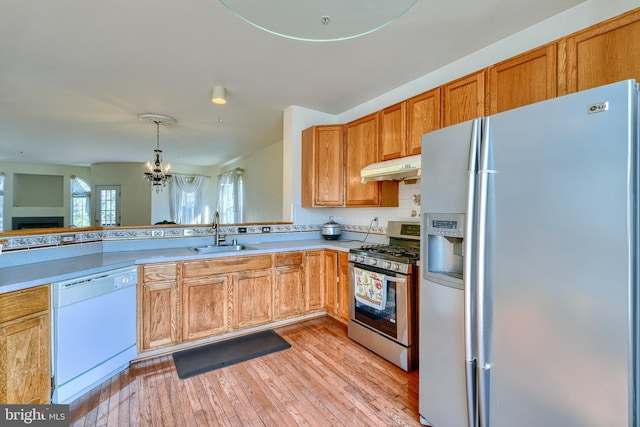 kitchen with sink, a notable chandelier, pendant lighting, stainless steel appliances, and light hardwood / wood-style floors