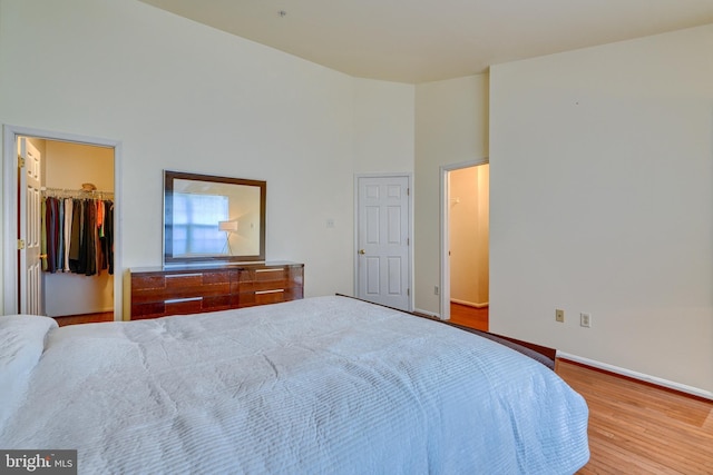 unfurnished bedroom with hardwood / wood-style floors, a walk in closet, a closet, and a high ceiling