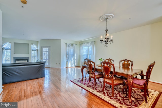 dining room with a healthy amount of sunlight, a notable chandelier, and light hardwood / wood-style flooring