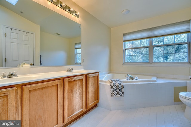 bathroom with vanity, tile patterned floors, tiled bath, and toilet