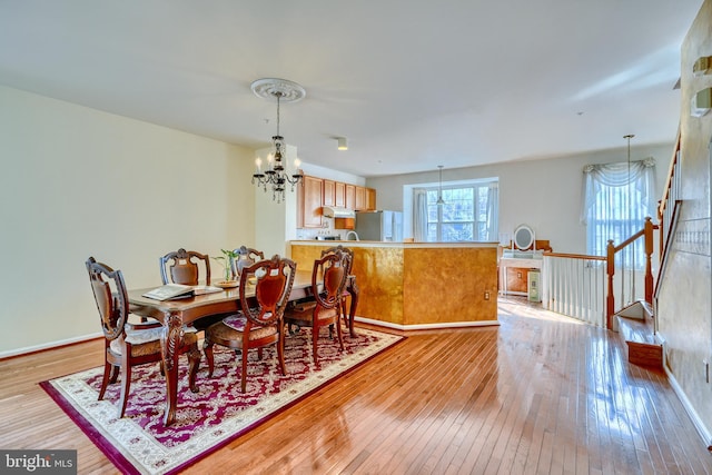 dining space with light hardwood / wood-style floors and a chandelier